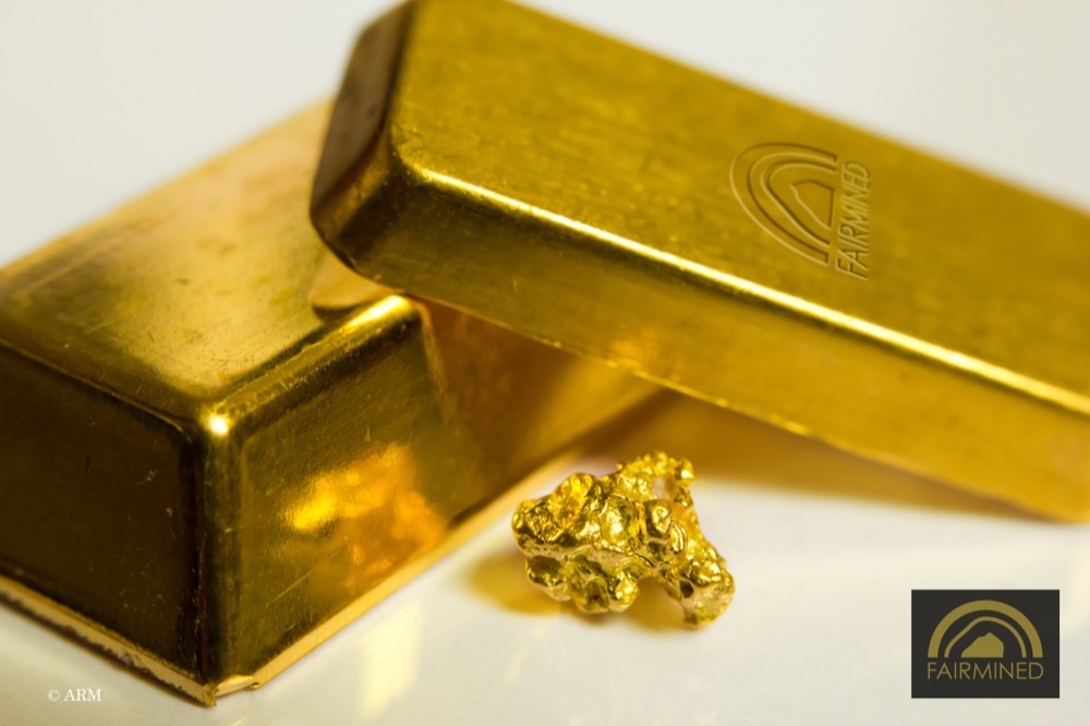 A Fairmined stamped gold ingot beside raw gold